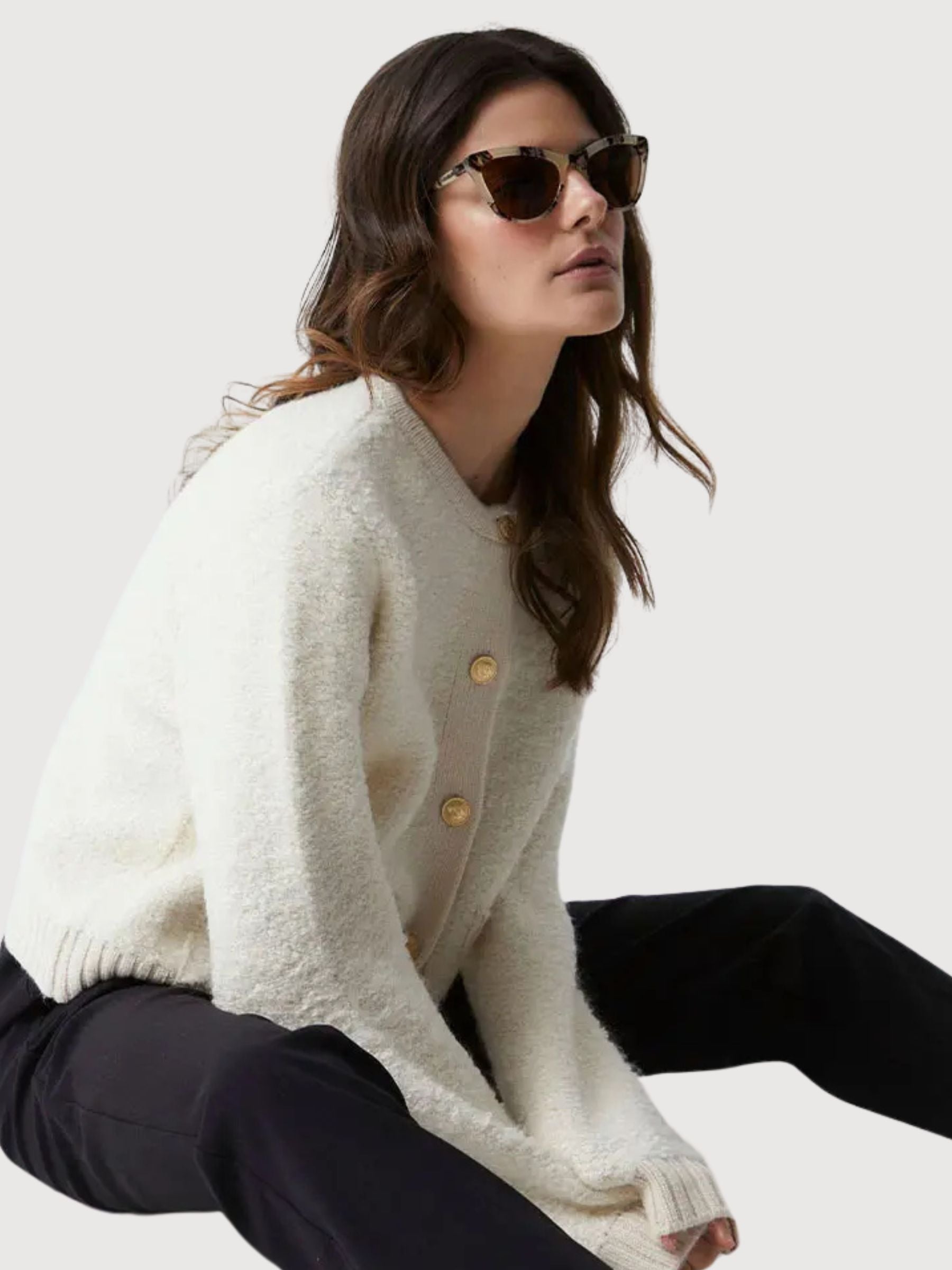 Woman wearing multicolor unisex sunglasses paired with a cozy white cardigan, showcasing eco-friendly style.