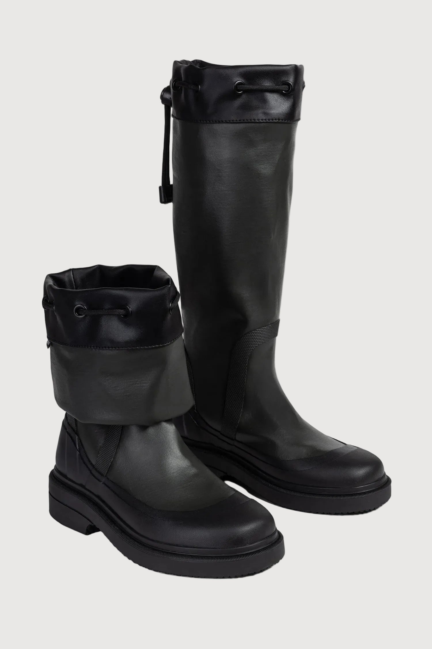 Pair of black knee-high boots on a light gray background