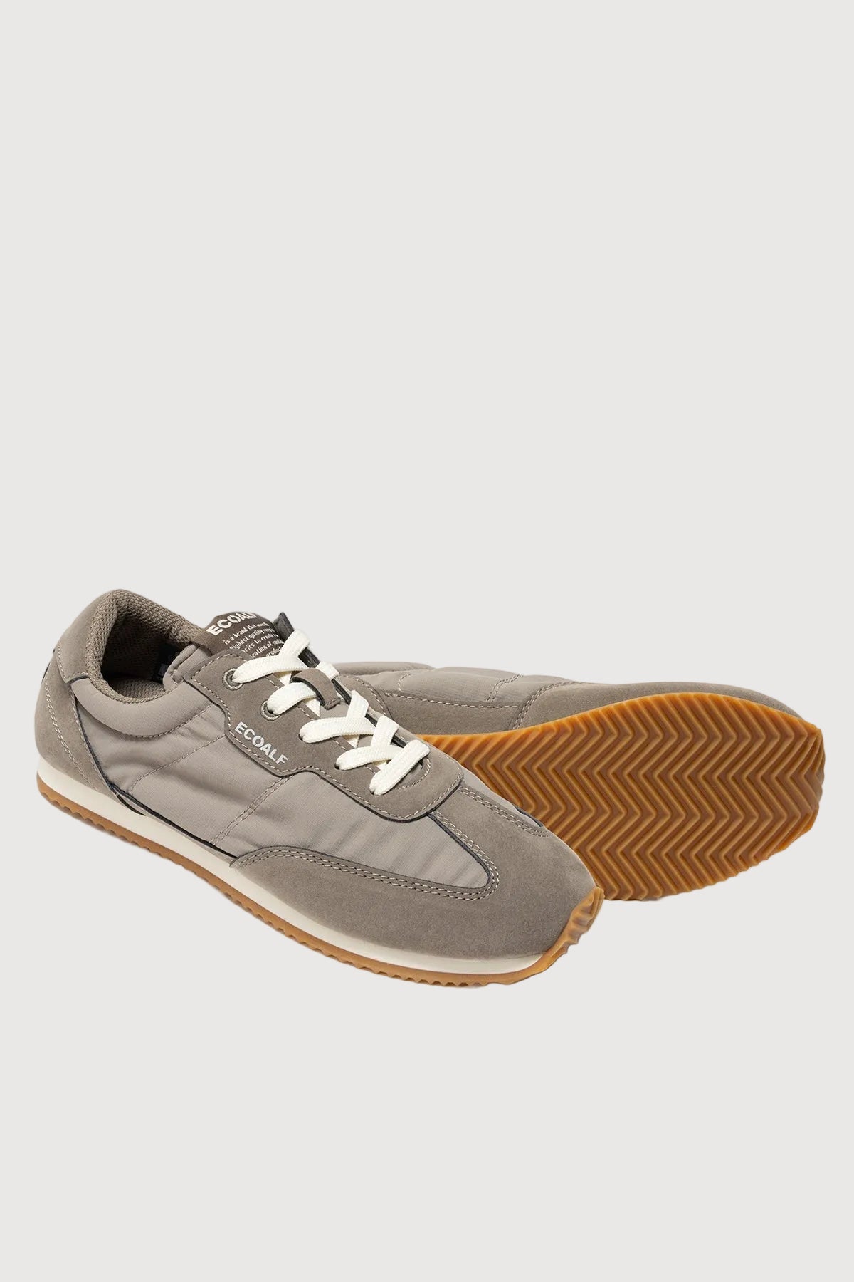 Pair of gray sneakers with a white sole on a light gray background